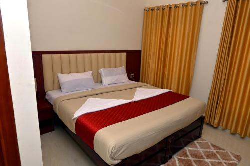 a bedroom with a bed with a red and white blanket at Swami Prasad Paradise hotel in Golitattu
