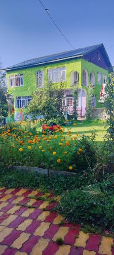a green building with flowers in front of it at Elizabeth paying guest house Tangmarg gulmarg in Gulmarg