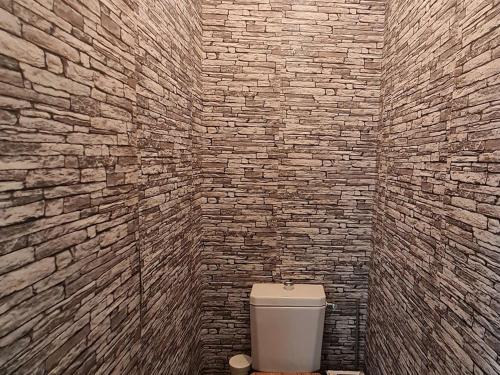 La salle de bains est pourvue de toilettes blanches et d'un mur en briques. dans l'établissement Gîte calme 3 chambres à Lunéville avec garage - FR-1-584-331, à Lunéville