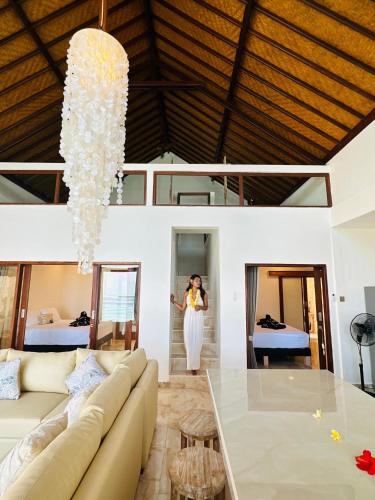 a woman standing in a living room with a chandelier at Bali Secrets Oceanfront Villas in Candidasa