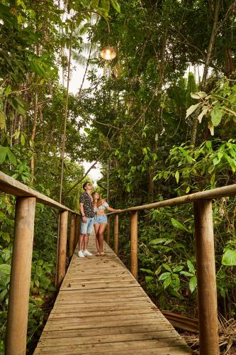 a man and a woman walking on a wooden bridge at Hotel Reserva de Piedemonte in Villavicencio