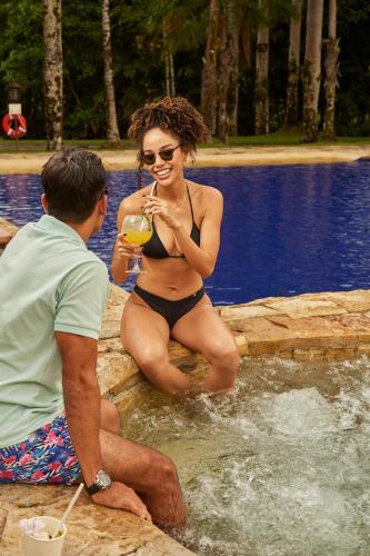 a man and a woman sitting in a swimming pool at Hotel Reserva de Piedemonte in Villavicencio