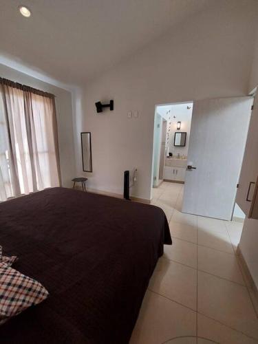 a bedroom with a black bed and a bathroom at Encantadora Casa en La Yesca cerca de poliforum in Santa Julia