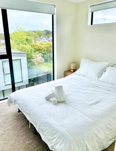 a white bed in a room with a large window at Townhouse in New Lynn in Auckland