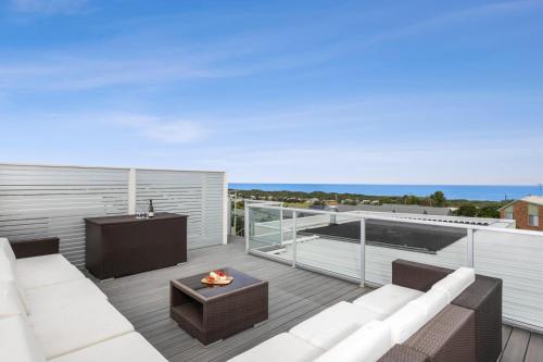 a patio with a couch and a table on a balcony at Sea Panorama on The Parade with pool in Ocean Grove
