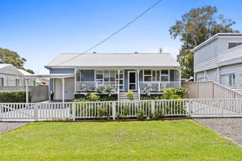 a white fence in front of a house at Spa & Chill Lodge in Budgewoi