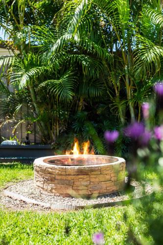 a fire pit in the grass in a yard at Spa & Chill Lodge in Budgewoi