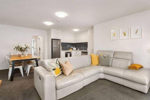 a living room with a white couch and a kitchen at Warm and inviting - Free carpark in Christchurch