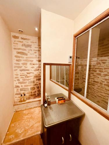 La salle de bains est pourvue d'un lavabo noir et d'une fenêtre. dans l'établissement Maison de Vignerons La Grange, à Noyers-sur-Serein