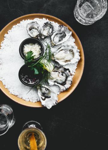 a plate of oysters and rice on a table with glasses at Kimpton - Grand Roatan Resort and Spa in West Bay