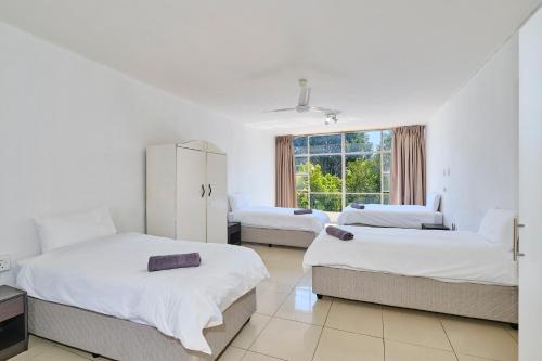 a white room with two beds and a window at Inn & Out Sandton Park in Johannesburg