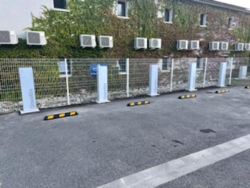 a parking lot with a fence next to a building at Hotel du Lac Foix in Foix