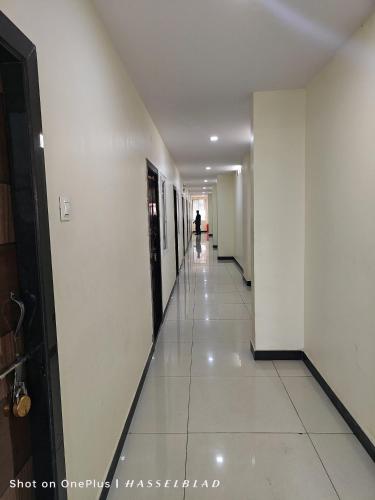 a long hallway with white walls and white tile floors at Chennakesava Grand in Rājahmundry