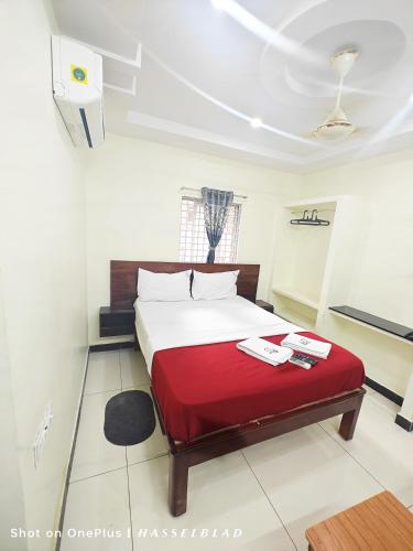 a bedroom with a bed with a red blanket at Chennakesava Grand in Rājahmundry