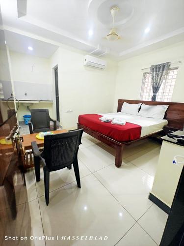 a bedroom with a bed and a table and a chair at Chennakesava Grand in Rājahmundry