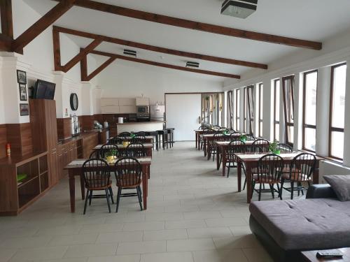 a dining room with tables and chairs and windows at Aranydukát Vendégház Tállya in Tállya