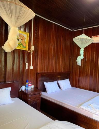 two beds in a room with wooden walls at TDB peter house in PhumÄ­ AnlÃ³ng Svay