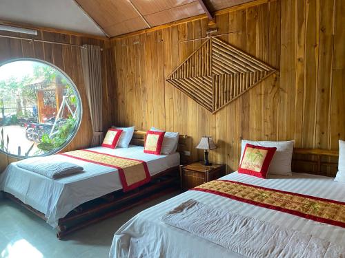 a bedroom with two beds and a large window at Tam Coc Charming Bungalow in Ninh Binh