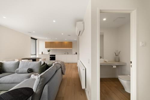 a living room with a gray couch and a kitchen at WARNING Extreme views 4 bed 3 bath luxury in Queenstown