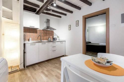 una cocina con armarios blancos y una mesa con un tazón. en Roommo Carmine, en Florencia