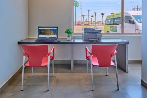a desk with two red chairs and a laptop on it at City Express Junior by Marriott Mexicali in Mexicali