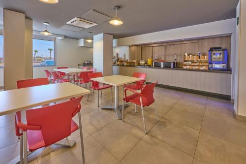 a restaurant with tables and red chairs and a counter at City Express Junior by Marriott Mexicali in Mexicali