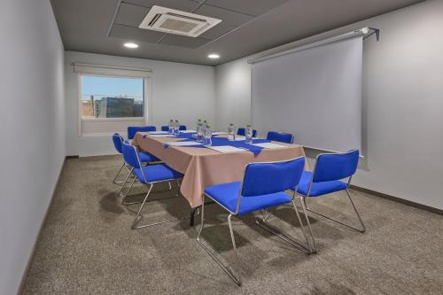 a conference room with a long table and blue chairs at City Express Junior by Marriott Mexicali in Mexicali