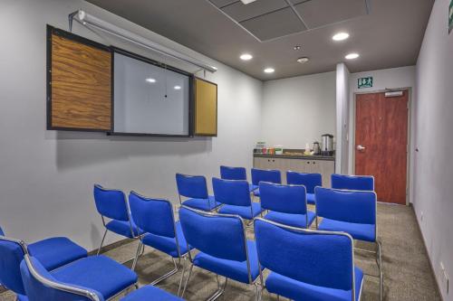 a conference room with blue chairs and a screen at City Express Junior by Marriott Mexicali in Mexicali