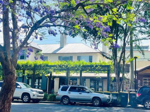 two cars parked in front of a building with purple flowers at Church Street Shop Top in Bellingen
