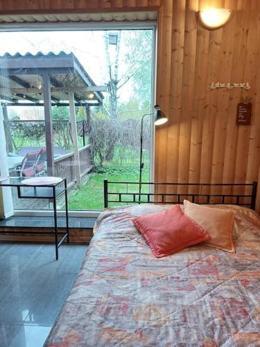 a bedroom with a bed and a table and a window at Cottage with fireplace and sauna in Pakalniškės
