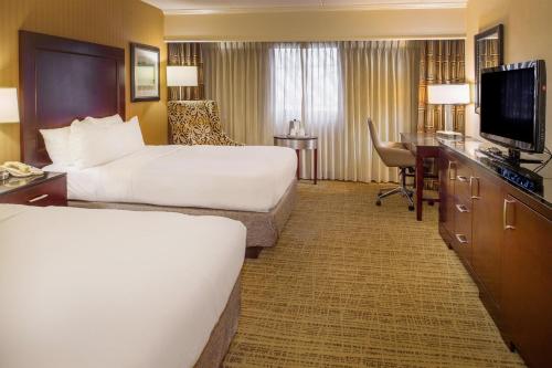a hotel room with two beds and a flat screen tv at Crowne Plaza Hotel St. Louis Airport by IHG in Bridgeton