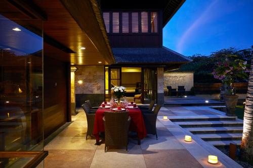 a dining room with a table and chairs on a patio at Pushpapuri Villa in Ketewel