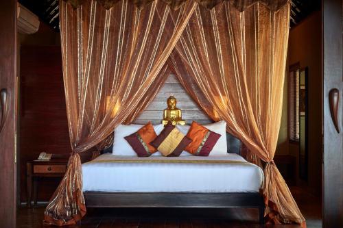 a bedroom with a canopy bed with pillows at Pushpapuri Villa in Ketewel