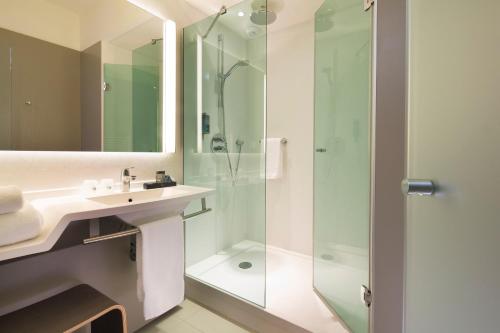 a bathroom with a sink and a shower at Oceania Le Jura Dijon in Dijon