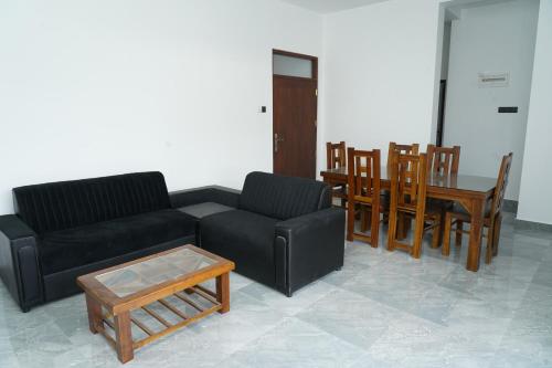 a living room with a black couch and wooden tables and chairs at The Alvis Nest in Kadawatha