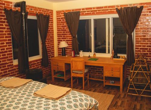 a bedroom with two beds and a desk and a window at Les Terrasses Himalayan Resort in Charikot