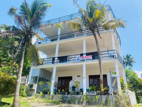 a building with palm trees in front of it at The Wave's Guest House in Mirissa