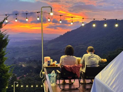 a couple sitting at a table watching the sunset at Peace Zone เขาค้อ in Khao Kho