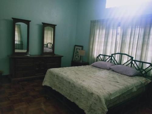 a bedroom with a bed and a dresser and a mirror at Pet-Friendly, Spacious Family Cottage, with Games Lounge & Near Beach in Port Dickson
