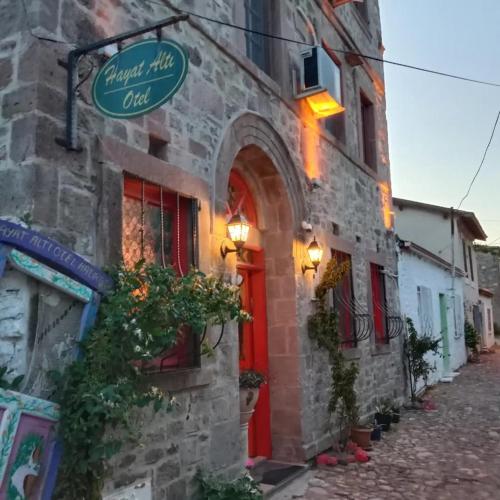 Un edificio con una puerta roja y un cartel en ella. en HAYAT ALTI OTEL ayvalık, en Ayvalık