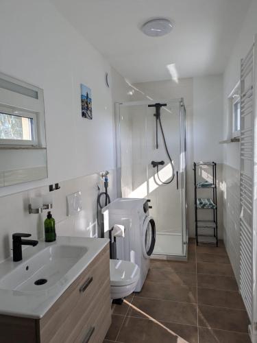 a white bathroom with a toilet and a sink at "Natur-Retreat am Bodden mit Kranichbeobachtung"-Haus kleiner Kranich in Neuendorf Hof