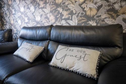 a leather couch with a pillow with the words be our guest at Stunning 3 bed House - Nr Kings Mill Hospital - 2 Parking Spaces, Wifi & Garden in Sutton in Ashfield