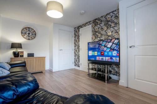 a living room with a couch and a flat screen tv at Stunning 3 bed House - Nr Kings Mill Hospital - 2 Parking Spaces, Wifi & Garden in Sutton in Ashfield