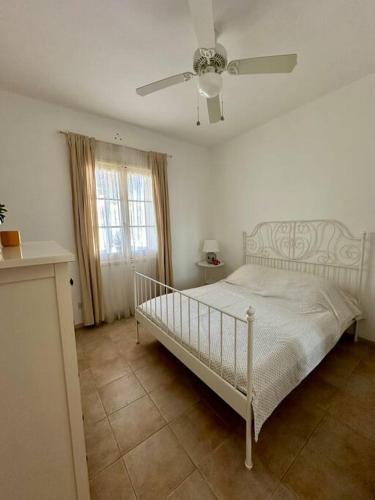 a bedroom with a white bed and a ceiling fan at Bizzilla - Family Friendly Maisonette in Xlendi