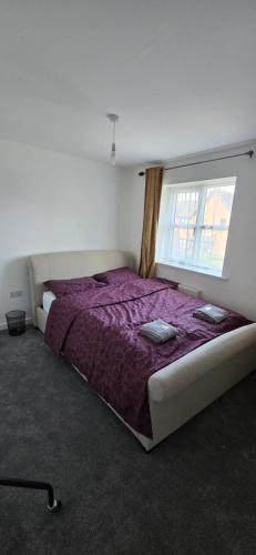 a bedroom with a bed with a purple comforter and a window at En-suite House, Minimum 3 nights bookings in Stockport