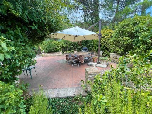 a patio with a table and an umbrella at Exclusive pool - wondrous views - biological Gardens - pool house - 12 guests in Marzolini