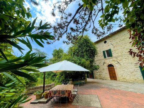a table with an umbrella in front of a building at Exclusive pool - wondrous views - biological Gardens - pool house - 12 guests in Marzolini