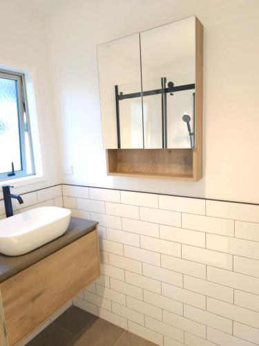 a bathroom with a sink and a mirror at Stylish Seabreeze Getaway in Mangawhai