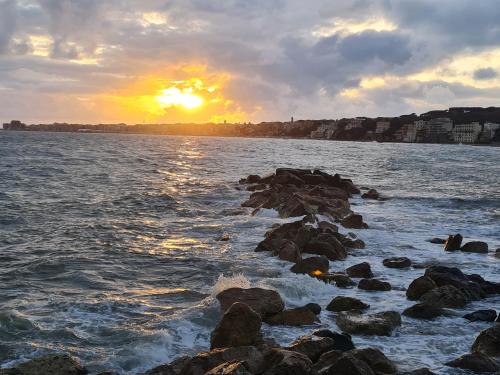 a sunset over a body of water with rocks at Un angolo al sole in Nettuno