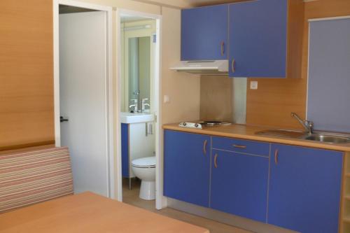 a blue kitchen with a toilet and a sink at Parque de Campismo Orbitur Vagueira in Gafanha da Boa Hora